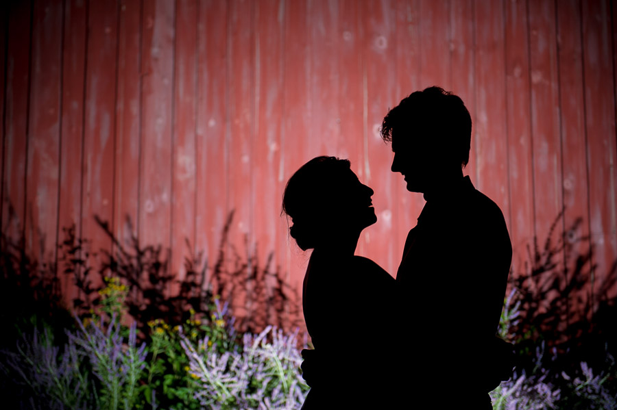 Romantic silhouette of bride and groom against barn at Indiana orchard wedding