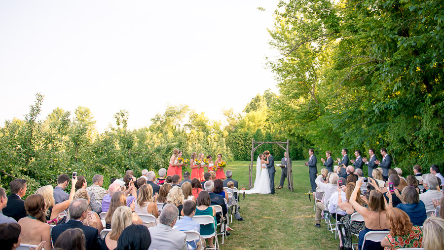 romantic and colorful summer wedding ceremony in apple orchard in the midwest
